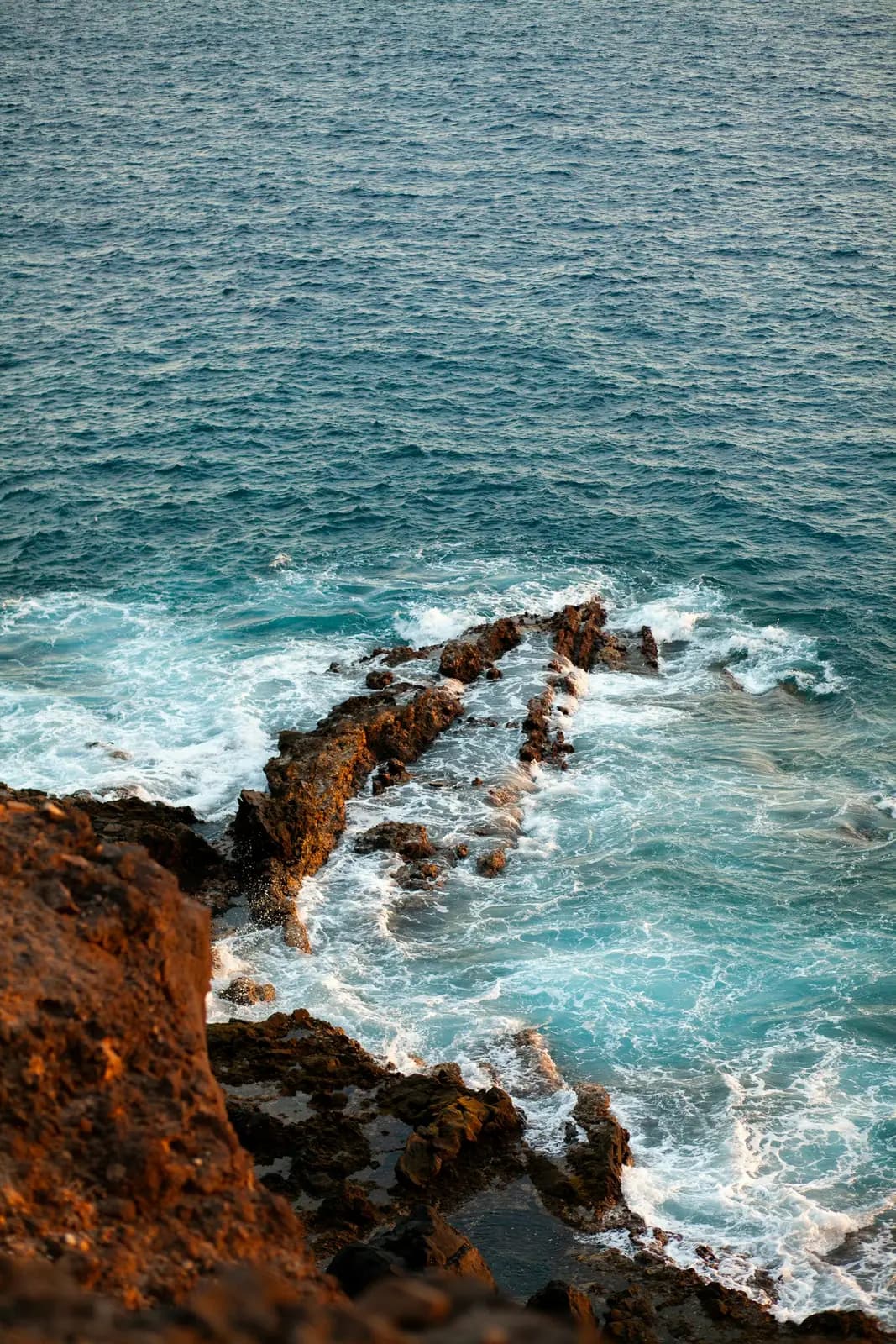 Waves breaking over dark volcanic rocks below the cliffs at Callao Salvaje