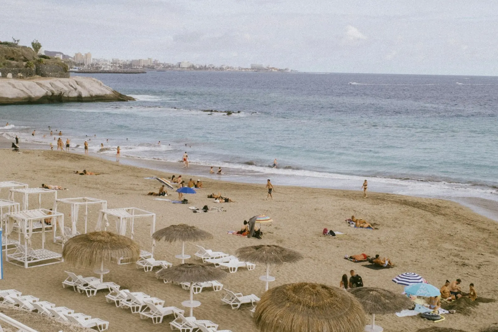 Playa del Duque in Costa Adeje with thatched parasols, white sun loungers and a calm sea