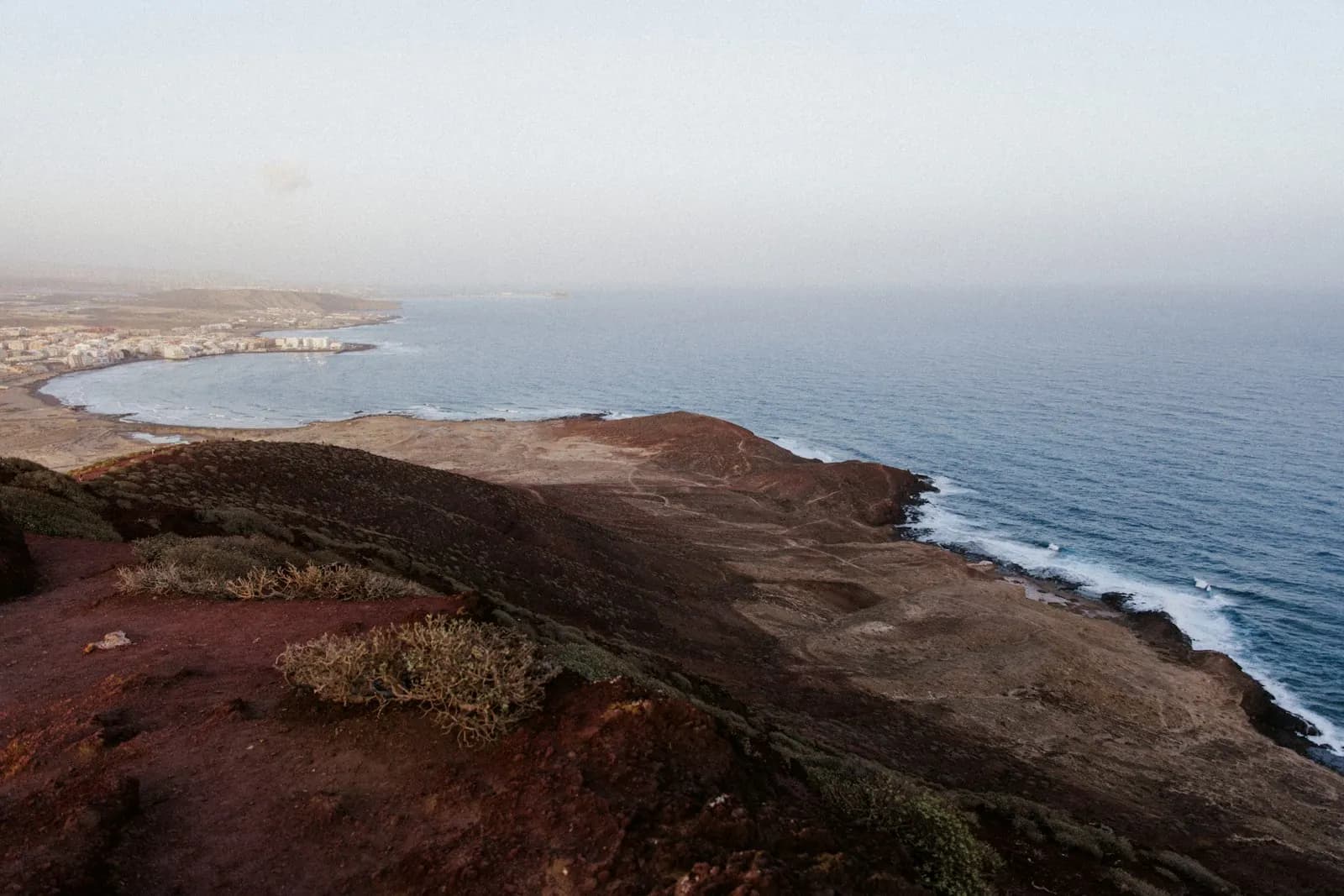 Vue depuis les pentes de la Montaña Roja, sur la terre volcanique rouge, vers la baie et la ville d'El Médano