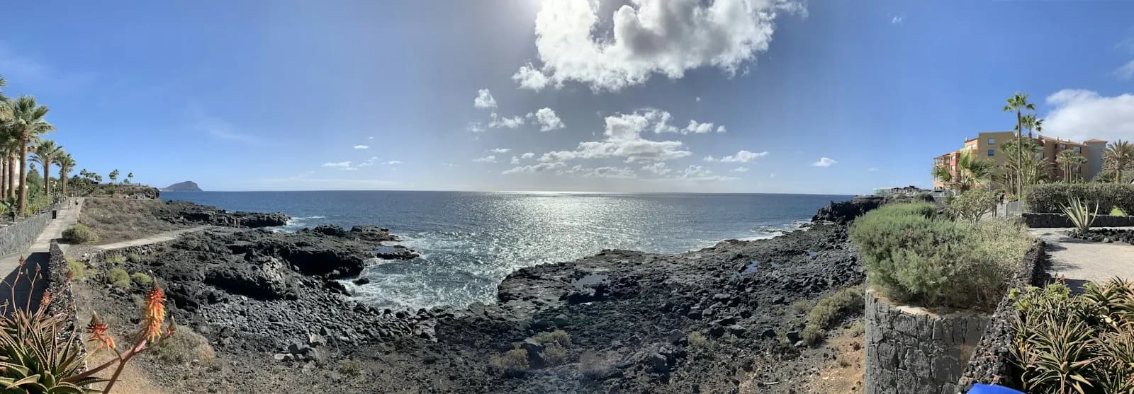 Panorama de la côte de roche volcanique noire et du sentier littoral de Golf del Sur, avec la Montaña Roja à l'horizon