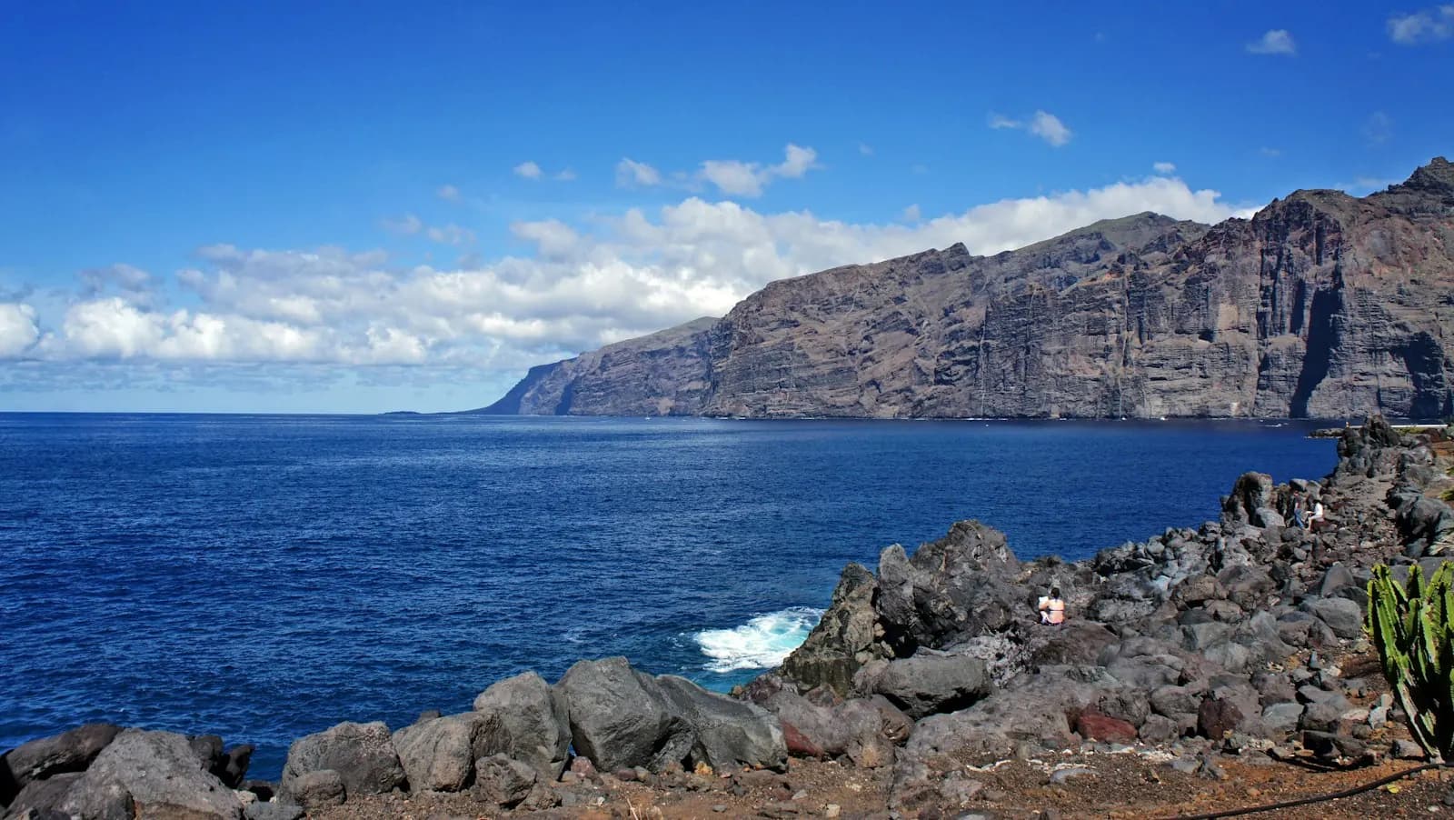 Los Gigantes cliffs rising sheer from the deep-blue Atlantic, seen from the rocky shore near the resort