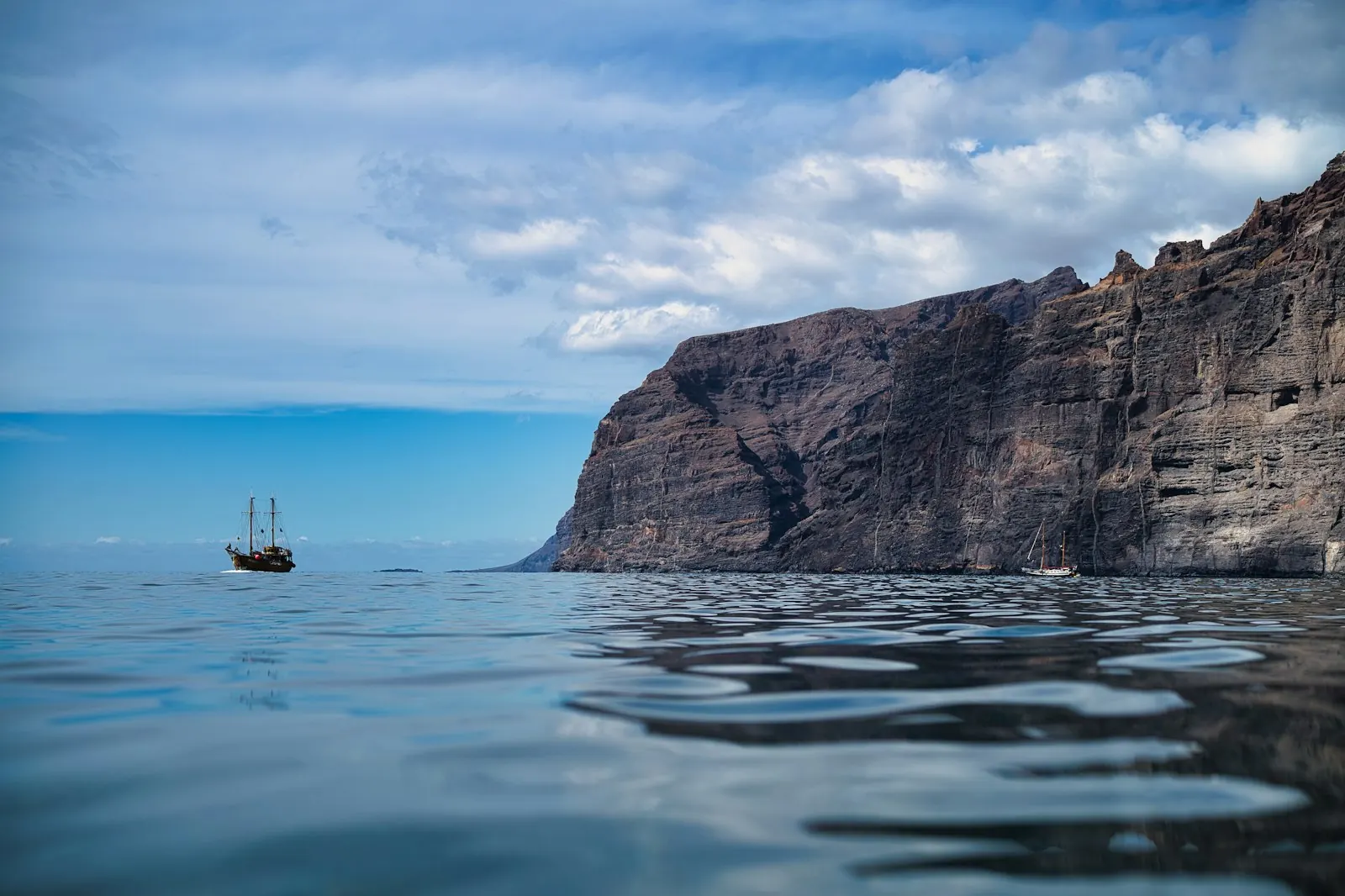 Excursion sailing boats at sea below the sheer Los Gigantes cliffs on a calm day