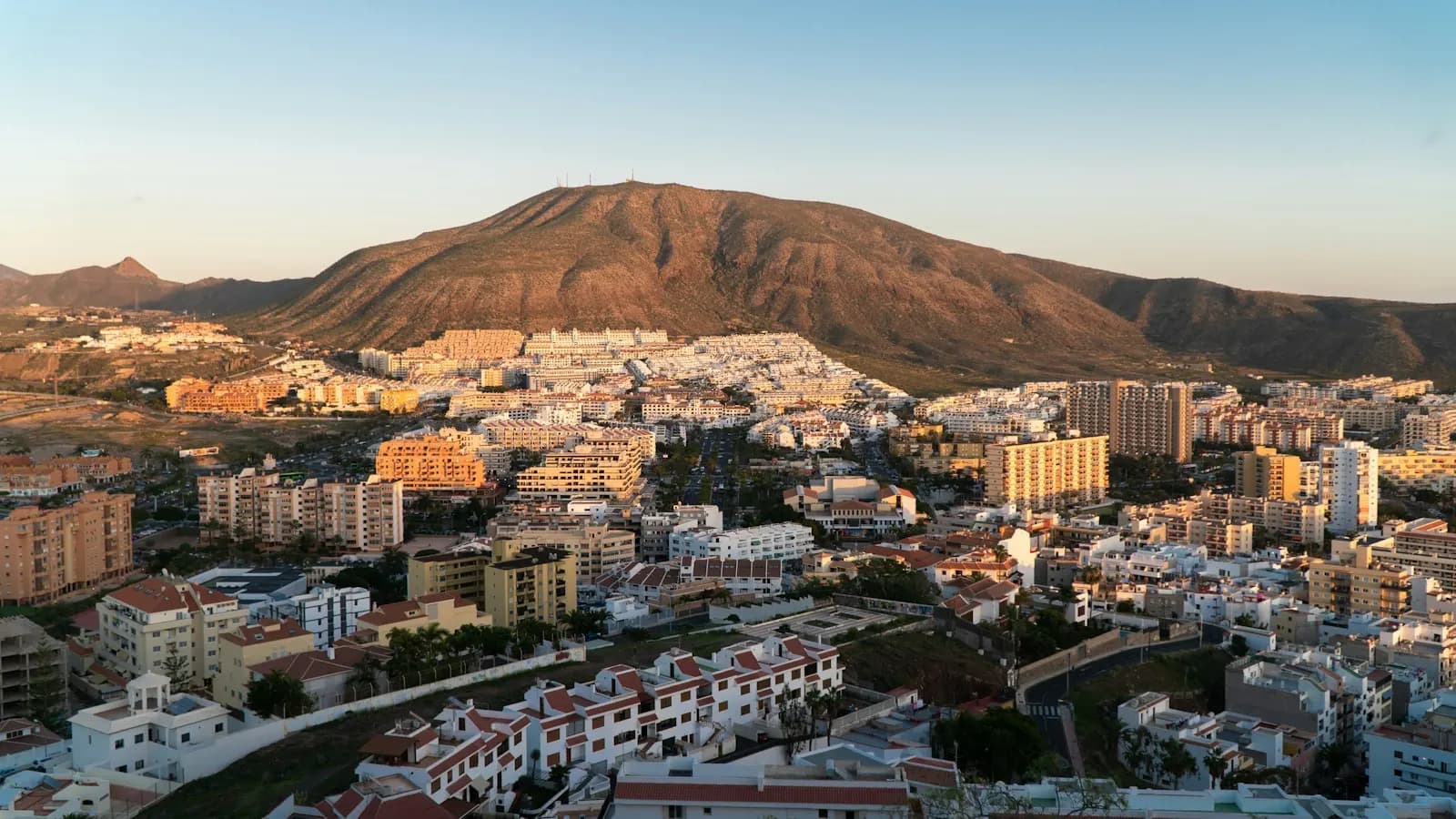 Los Cristianos all'ora dorata, con condomini e case bianche che salgono fino alle pendici della Montaña de Guaza
