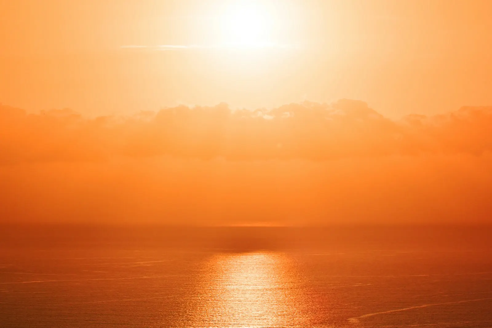 Orange sunset over the Atlantic seen from Costa Adeje, with the sun reflected on a calm sea