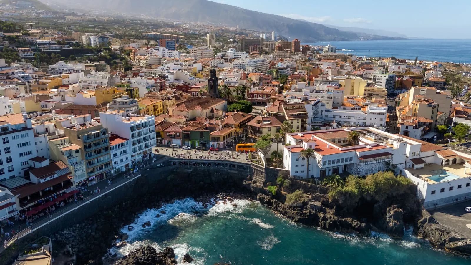 Veduta aerea del centro storico di Puerto de la Cruz, con il campanile, il lungomare e le onde sugli scogli neri