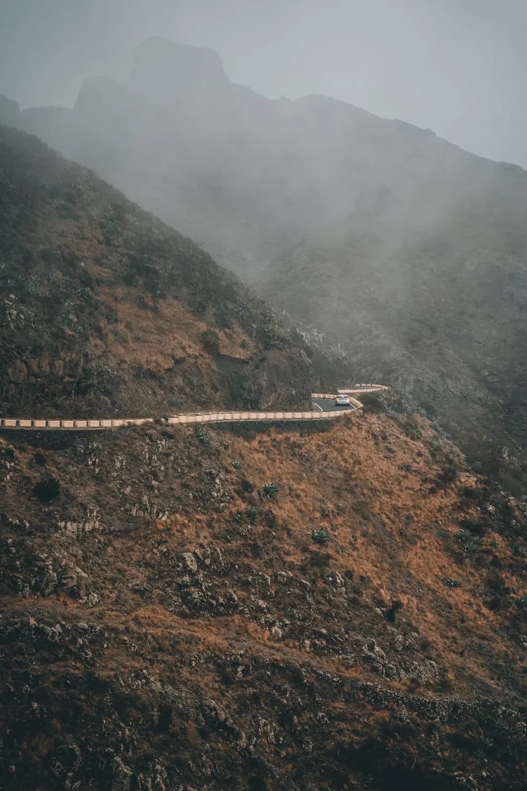 Nuvole basse su una strada di montagna tortuosa lungo un pendio ripido nel nord di Tenerife