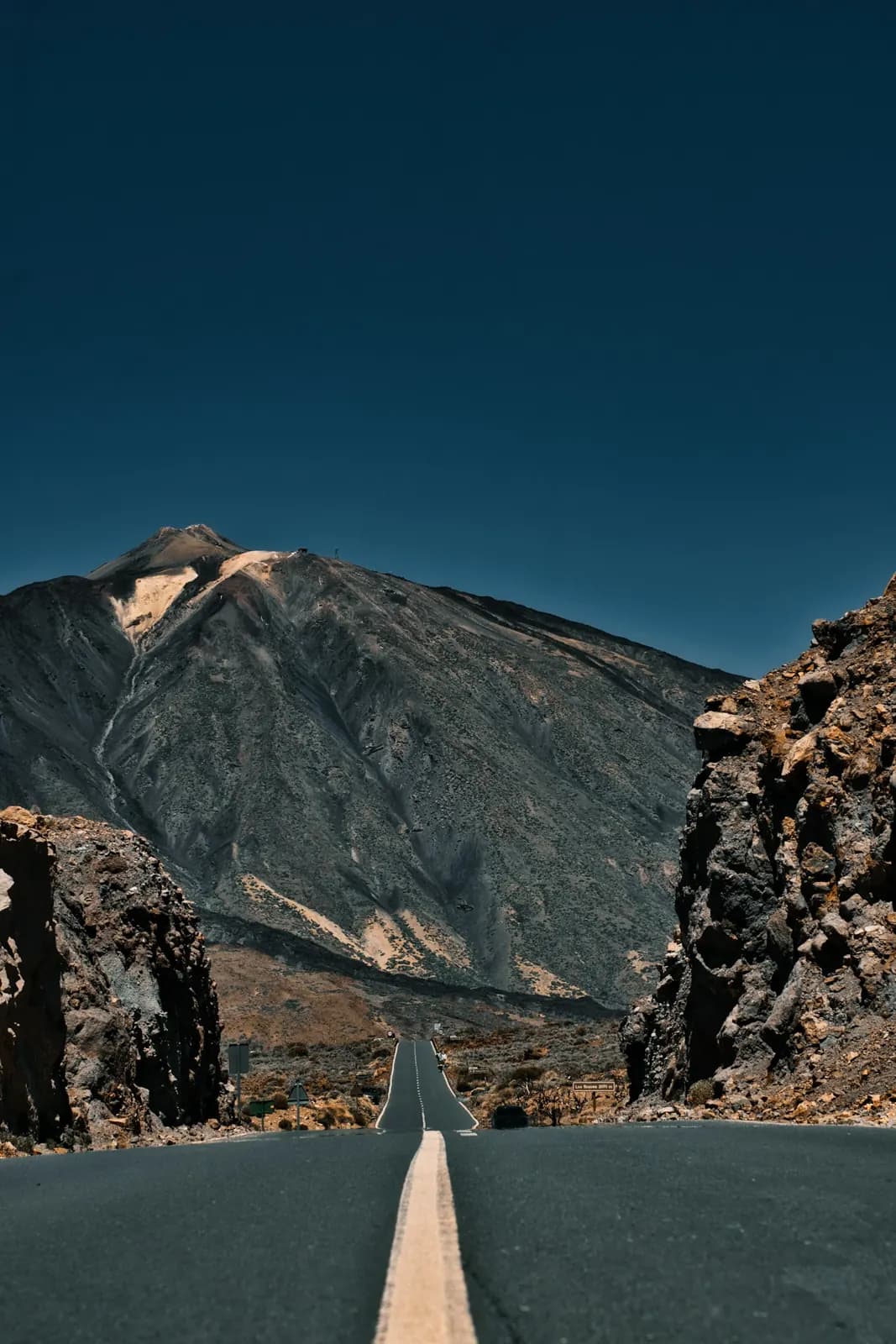 The road through Teide National Park with the summit of Mount Teide rising ahead between volcanic rock walls