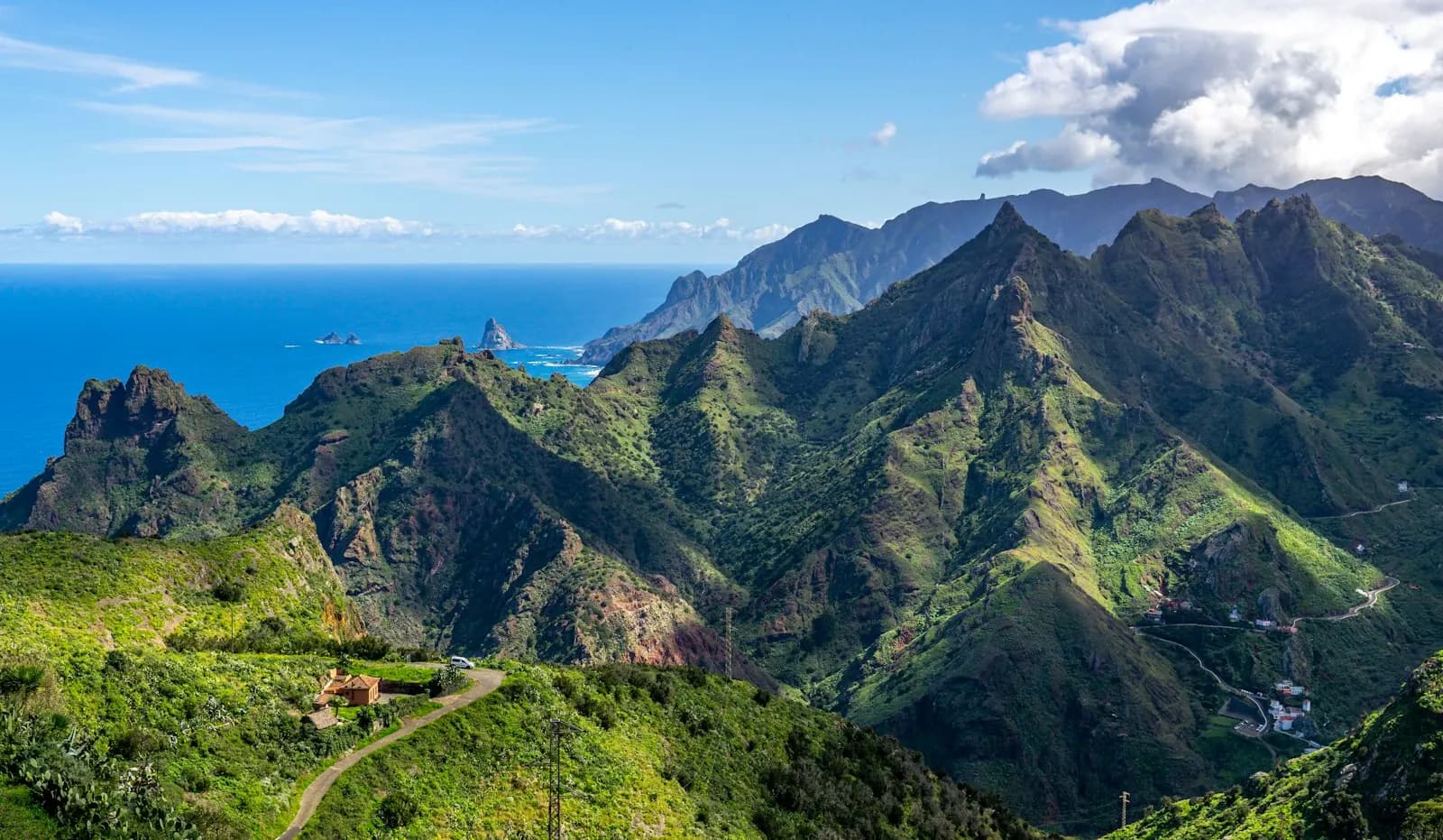 Picos verdes y escarpados del macizo de Anaga, en el noreste de Tenerife, con una carretera sinuosa y roques en el Atlántico
